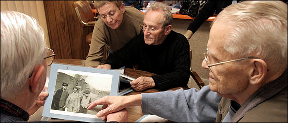 Vernon Tott, right, was with the 84th Infantry Division in April 1945 at the liberation of Ahlem, a Nazi labor camp in Germany. Two survivors of the camp, Henry Shery, left, and Lucjan Barr, with his wife, Ruth, looked at Mr. Tott's photos from Ahlem at his Sioux City, Iowa, home last week.
